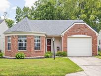 Charming brick home featuring a well-manicured lawn, attached garage, and lovely front garden at 6637 Sundown S Dr, Indianapolis, IN 46254