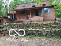 Exterior elevation with weathered siding, stone wall, and covered porch at 8803 S Sleepy Hollow Rd, Waldron, IN 46182