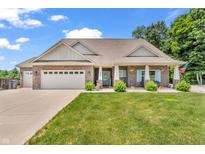 Charming brick home with a well-manicured lawn, attached garage, and a quaint covered porch at 9231 E Poynter Dr, Morgantown, IN 46160