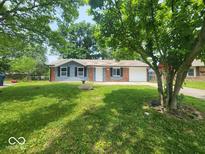 Charming single-story home with a manicured lawn and mature trees providing shade at 9526 Burrwood Ct, Indianapolis, IN 46235