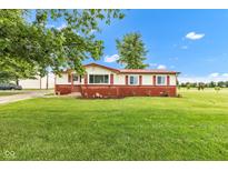Charming ranch-style home with a well-manicured lawn, colorful landscaping, and a red accent roofline at 10965 W Base Line Rd, Jamestown, IN 46147