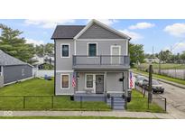 Charming two-story home with a balcony, well-maintained lawn, and a classic gray exterior at 134 N Elder Ave, Indianapolis, IN 46222