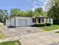 Inviting single-story home with a detached garage and ample parking space on a sunny day at 1649 N Arsenal Ave, Indianapolis, IN 46218