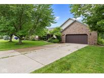 Charming brick home featuring an attached two-car garage, and lush landscaping on a sunny day at 476 Turnberry Ct, Avon, IN 46123