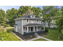 Charming two-story home with a covered front porch and well-maintained landscaping. Trees provide shade at 4836 Winthrop Ave, Indianapolis, IN 46205