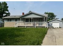 Charming home featuring a cozy porch, stone accents and a detached garage, perfect for comfortable living at 4908 Elmhurst Dr, Indianapolis, IN 46226