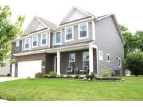 Beautiful two-story home featuring a brick facade, well-manicured lawn, and charming front porch with seating at 10113 Gallop Ln, Fortville, IN 46040