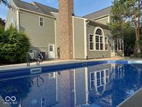 Back of home featuring an in-ground pool with blue water and reflection of the home's architecture at 13262 Landwood Dr, Fishers, IN 46037