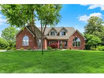 Charming brick home with a well-manicured lawn and mature trees under a sunny blue sky at 1411 N Claridge Way, Carmel, IN 46032