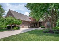 Beautiful brick home featuring a three-car garage, manicured lawn, and mature trees at 3545 Inverness Blvd, Carmel, IN 46032