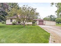 Charming ranch-style home featuring a well-manicured lawn, mature tree, and a convenient attached garage at 4010 S Bazil Ave, Indianapolis, IN 46239