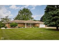 Charming brick ranch home featuring a lush green lawn, mature trees, and a two-car attached garage at 5749 Teresa Dr, Alexandria, IN 46001