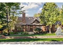 Charming brick home with mature trees, brick wall and an inviting front yard with manicured lawn at 5946 Guilford Ave, Indianapolis, IN 46220