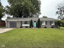 Charming one-story home with a well-manicured lawn, gray brick facade, and an inviting blue front door at 729 Maple Ln, Brownsburg, IN 46112