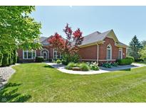 Charming brick home featuring lush landscaping, healthy green lawn and beautiful curb appeal at 7413 Misty Woods Ln, Indianapolis, IN 46237
