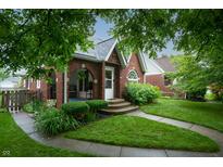 Charming brick home featuring a beautifully landscaped front yard with a welcoming porch and walkway at 828 N Butler Ave, Indianapolis, IN 46219
