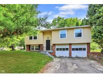 Split-level home featuring a two-car garage, siding, and landscaped front yard at 8920 Caminito Rd, Indianapolis, IN 46234