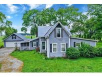 Charming two-story home with blue siding, well-maintained lawn, and mature trees, offering a peaceful setting at 9237 N 500 W, Fountaintown, IN 46130