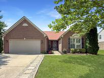 Charming brick home featuring an attached garage, a beautifully landscaped yard, and a welcoming walkway at 9302 N Bayland Dr, McCordsville, IN 46055