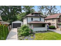 Charming two-story home with a covered front porch, neat landscaping, and a detached garage at 953 E 34Th St, Indianapolis, IN 46205