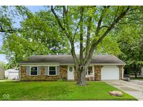 A well-maintained brick home with mature trees, a front lawn, and attached one car garage at 99 Old Trail Dr, Bargersville, IN 46106