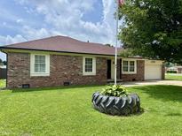 Charming brick home with lush green lawn and unique tire planter at 100 Justin Dr, Mooresville, IN 46158