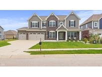 Beautiful two-story home with a well-manicured lawn and three-car garage on a sunny day at 10811 Wild Orchard Ln, Indianapolis, IN 46239