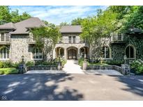 Stunning stone home featuring arched entry, balconies, and mature landscaping at 11557 Willow Springs Dr, Zionsville, IN 46077
