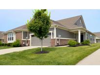 Inviting front yard and entrance of a gray and brick home with a well manicured green lawn at 17303 Lillian St, Westfield, IN 46074