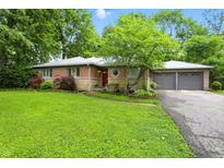 Charming single story home with brick and stone exterior, mature trees, and a well-manicured lawn at 4340 Ashbourne Ln, Indianapolis, IN 46226