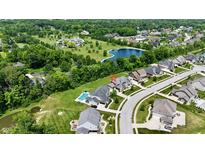 An aerial view of a suburban neighborhood showcasing the property with a pool nestled among lush trees at 5706 Bentbrook Dr, Bargersville, IN 46106