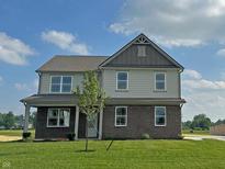 Inviting two-story home with brick accents, a covered porch, and well-maintained lawn on a beautiful day at 7909 Magnolia St, New Palestine, IN 46163
