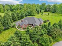 Expansive aerial view of brick home surrounded by lush landscaping and mature trees on a sprawling green lot at 8301 Cooper Ln, Zionsville, IN 46077