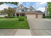 Charming two-story brick and white home with a well-manicured lawn and a three-car garage at 8904 Carnation Dr, Noblesville, IN 46060