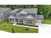 Beautiful two-story home boasts a brick facade, attached garage, and a well-manicured lawn with mature trees at 15546 Senita Ln, Fishers, IN 46037