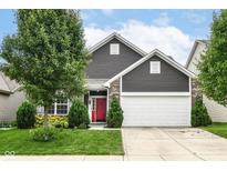 Charming home with a red door, manicured lawn, and attached two-car garage on a sunny day at 561 Farnham Dr, Westfield, IN 46074