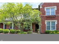 Charming brick home with lush landscaping, including a mature tree and manicured bushes at 6691 Beekman Pl, Zionsville, IN 46077