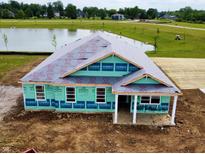 An exterior view of a home under construction with a pond in the background in a lovely community at 7877 Magnolia St, New Palestine, IN 46163