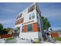 Modern three-story home featuring a white exterior with wood accents, balconies, and a picket fence at 806 Shelby St, Indianapolis, IN 46203