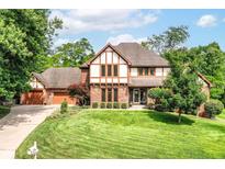 Charming Tudor-style home with a well-manicured lawn, mature trees, and attached garage at 8534 Helmsman Cir, Indianapolis, IN 46256