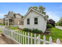 Charming cottage-style home featuring a classic white picket fence and well-maintained lawn and landscaping at 905 Buchanan St, Indianapolis, IN 46203