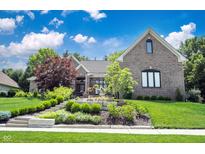 Charming brick home featuring lush landscaping, a stone walkway, and a well-maintained lawn at 10707 Burning Ridge Ln, Fishers, IN 46037
