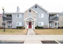 Inviting two-story condo building with a red front door and manicured landscaping at 209 Faulkner Ct # 102, Carmel, IN 46032