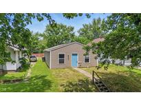 A charming single-story home featuring tan siding, a bright blue door, and a small front yard at 2524 E 17Th St, Indianapolis, IN 46218