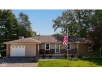 Charming single-story home featuring a cozy front porch, an attached garage, and a neatly maintained front lawn at 453 N 275 E, Columbus, IN 47203
