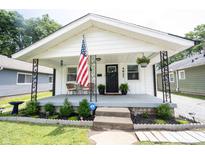 Charming home featuring a quaint covered porch, adorned with an American flag and seating area at 4927 Caroline Ave, Indianapolis, IN 46205