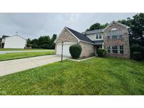 Two-story home featuring a brick facade, attached garage, and a well-manicured front lawn at 5938 Tybalt Ln, Indianapolis, IN 46254