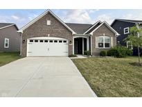 Charming brick home featuring an attached two-car garage and well-manicured lawn at 6729 Birmingham Ave, McCordsville, IN 46055