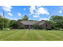 Charming brick home with a beautifully landscaped front yard and lush green lawn under a blue sky at 8818 Mathews Rd, Indianapolis, IN 46259