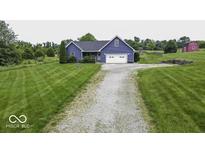 Charming blue home with a two-car garage, spacious yard, and a long gravel driveway at 911 Centennial Rd, Martinsville, IN 46151
